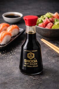 Bote de salsa de soja natural de la marca Shoda con pezas de sushi de fondo